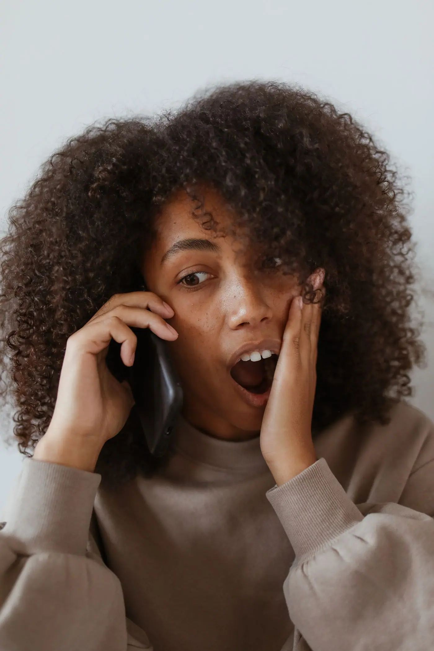 A woman reacting with surprise while holding a phone.