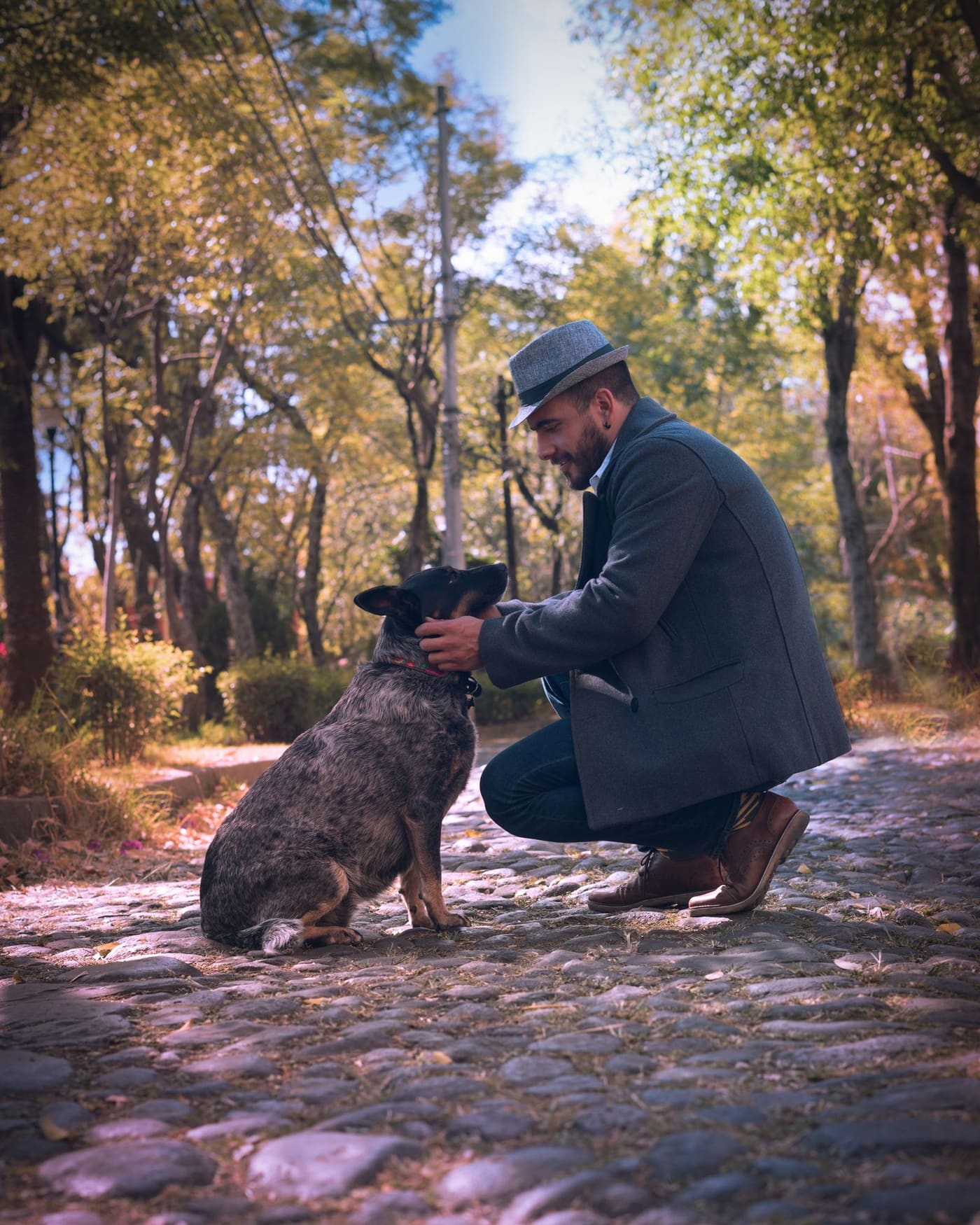 A man crouching to greet his dog on a path in a Mexico City park.