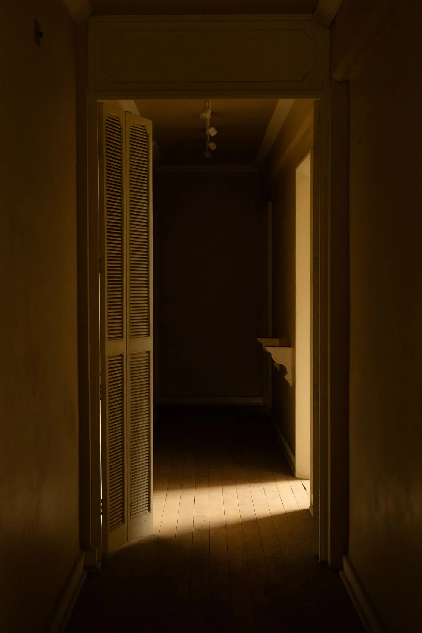 A dim corridor in a building in Mexico City with warm light coming through a partly open door.