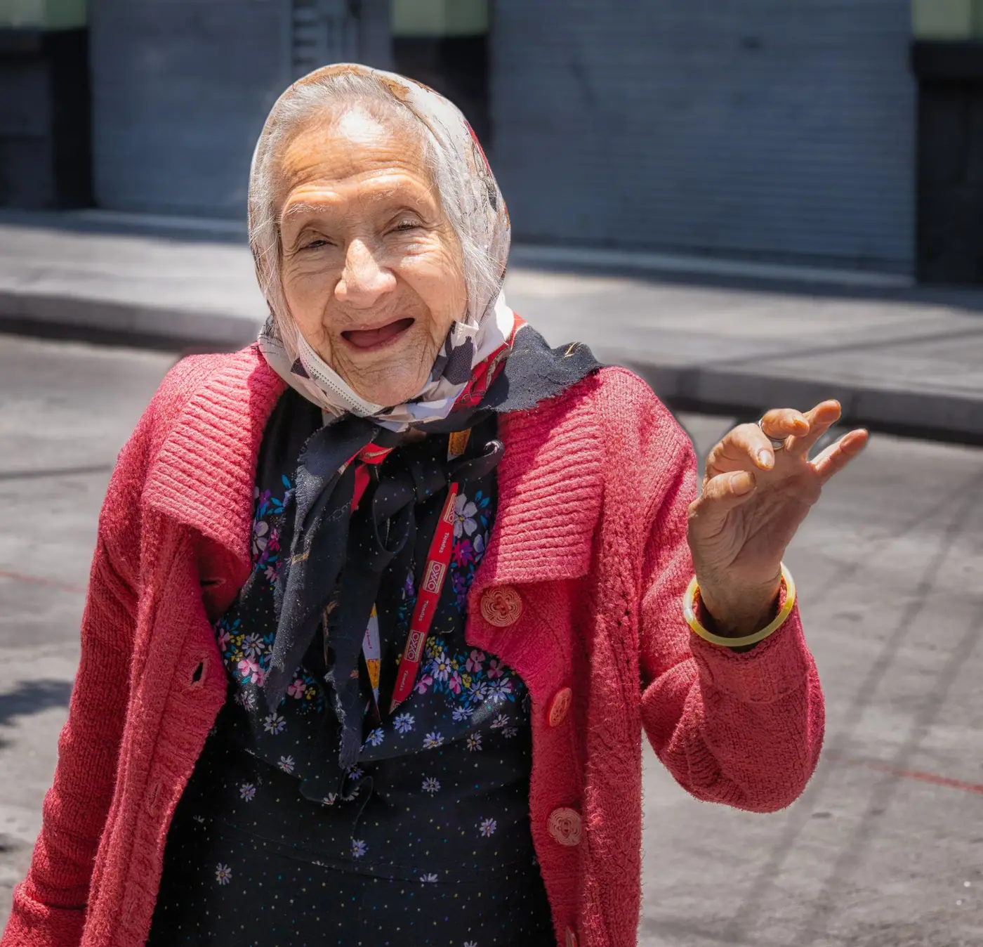 A smiling older woman in a red cardigan outdoors in Mexico City.