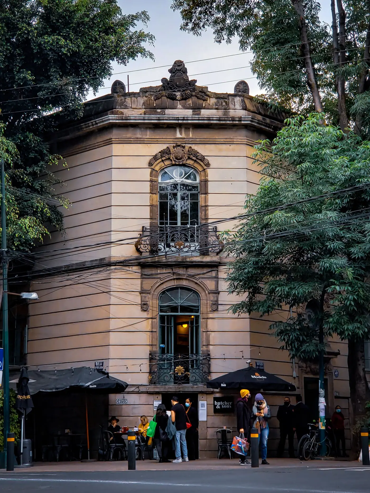A corner cafe building with people outside on a Mexico City street.