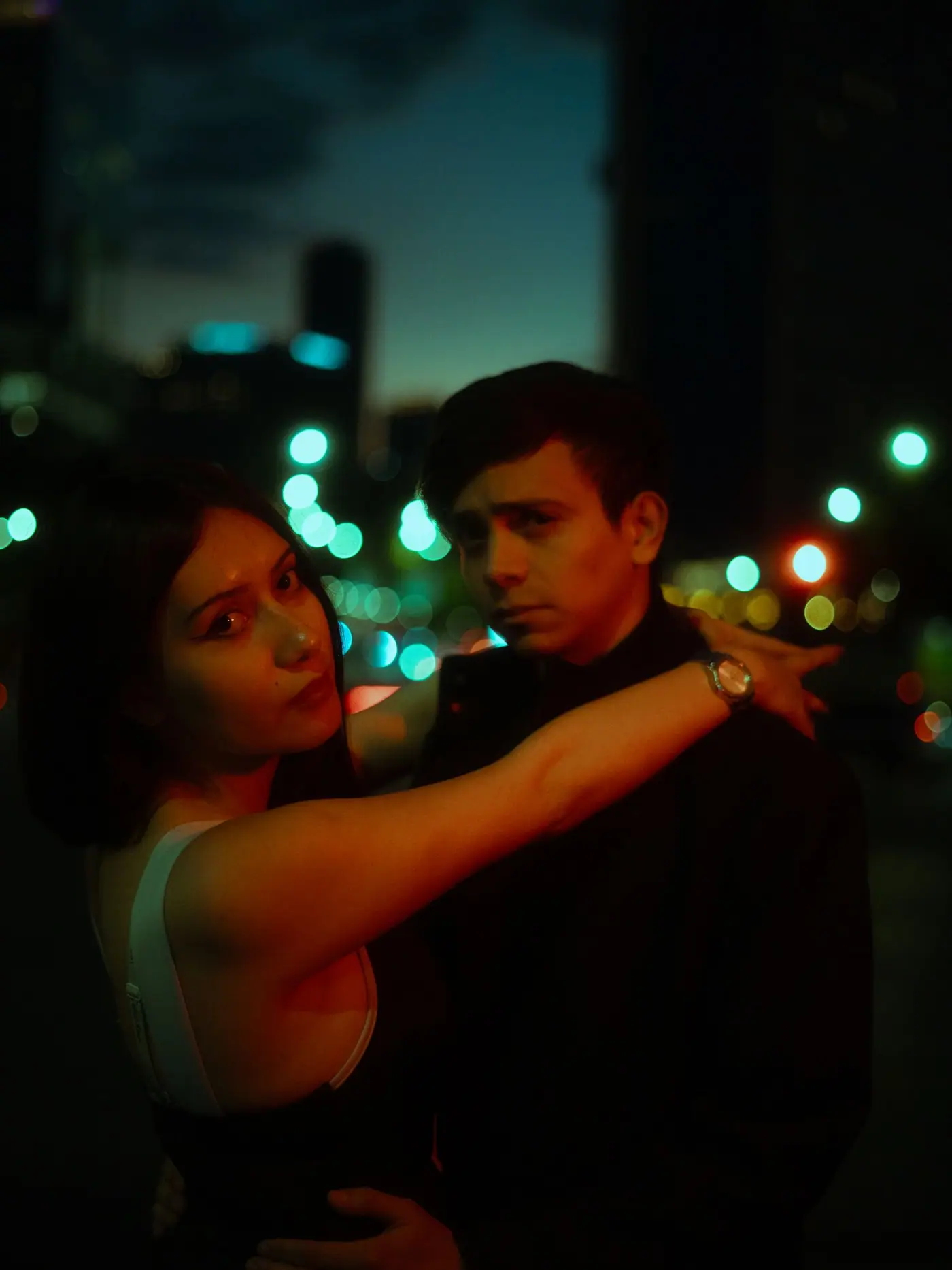 A young couple embracing at night under city lights in Mexico City.