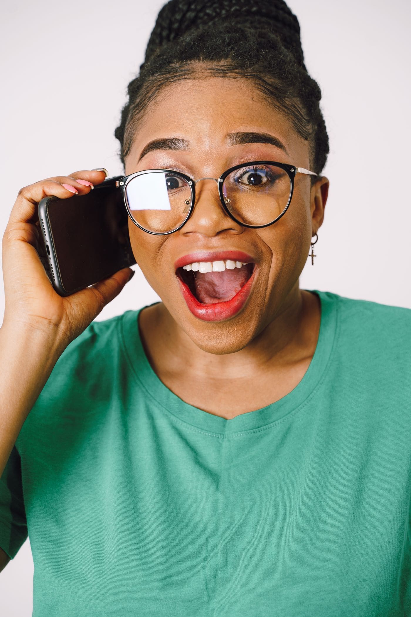 A woman in glasses reacting while talking on a smartphone.