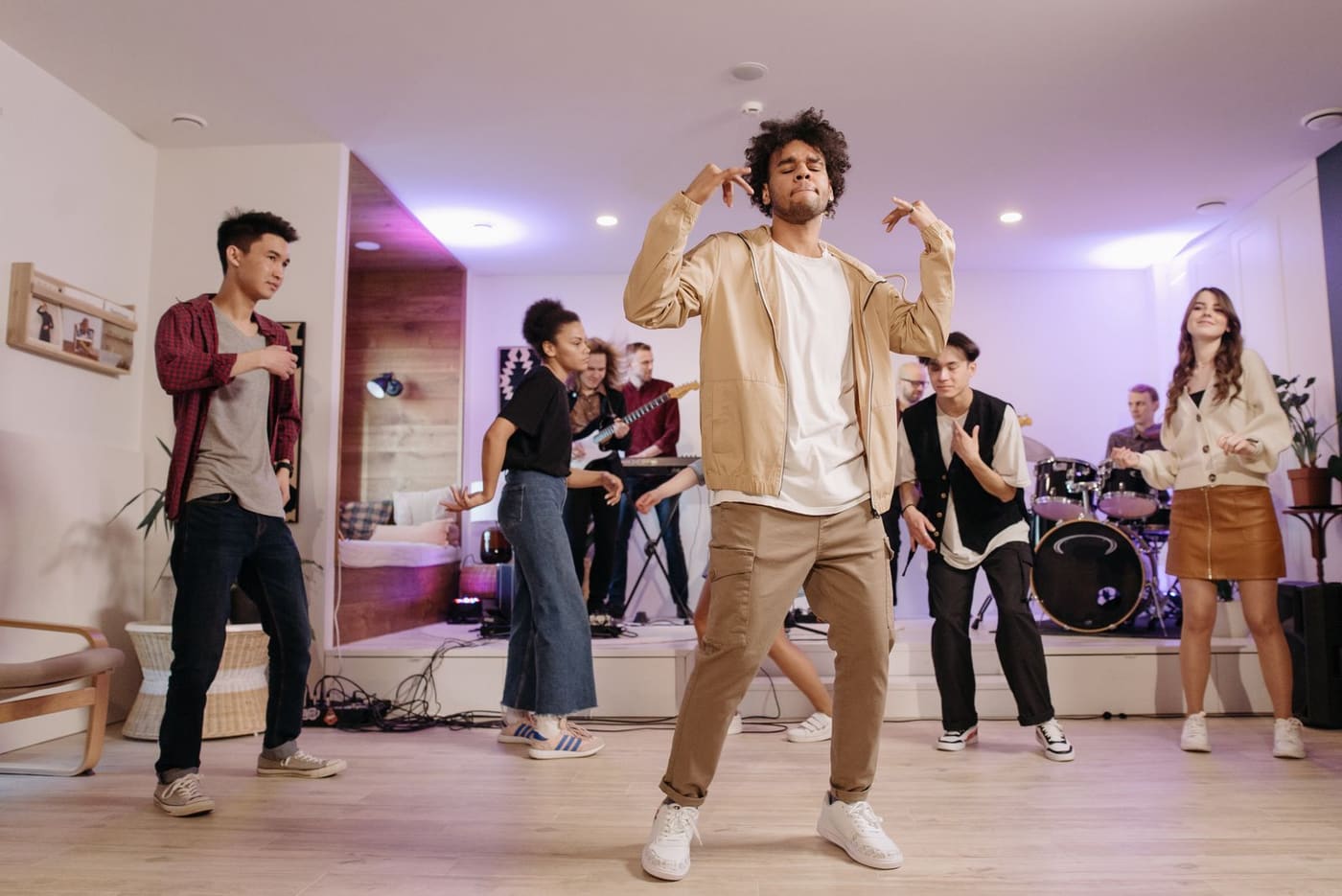 A group of adults dancing to live music at a home party.