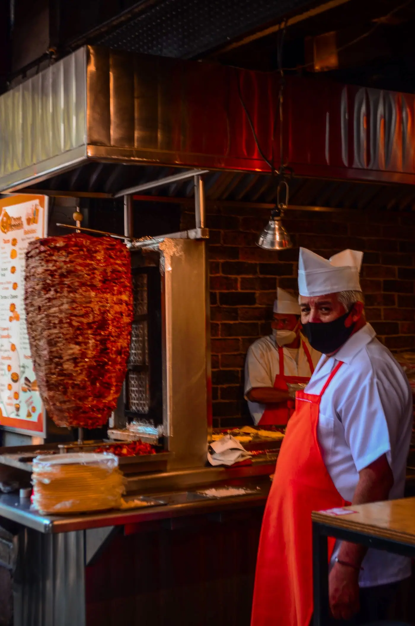 Cooks preparing tacos al pastor behind the counter of a taqueria in Mexico City.