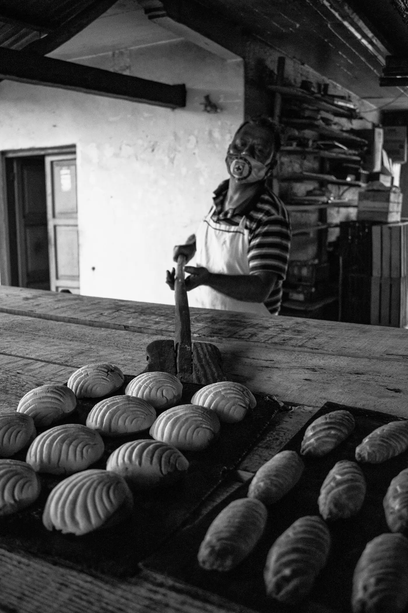 A baker laying loaves out on a table in a traditional bakery in Pahuatlan, Puebla.
