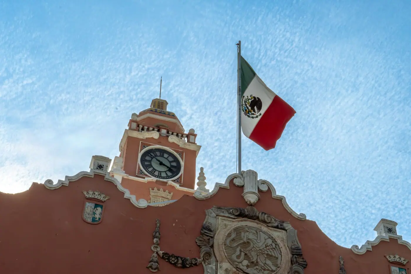 The clock tower of the municipal palace in Merida with a Mexican flag.