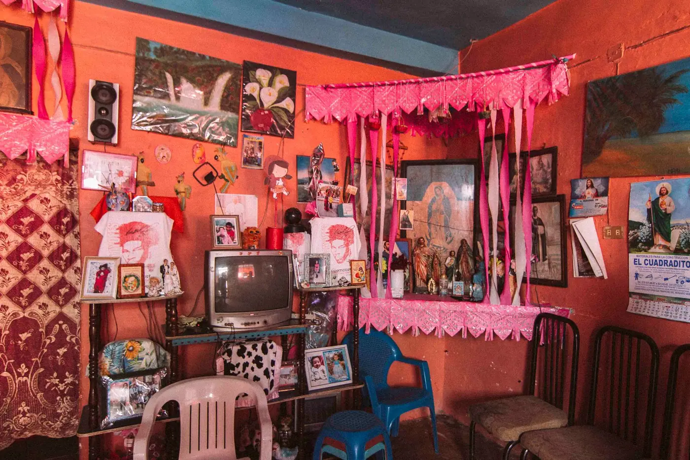 A room in a Mexican home with framed religious pictures and figurines on the wall.