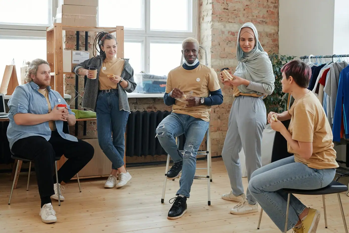 A diverse group of adults sharing food and conversation indoors.
