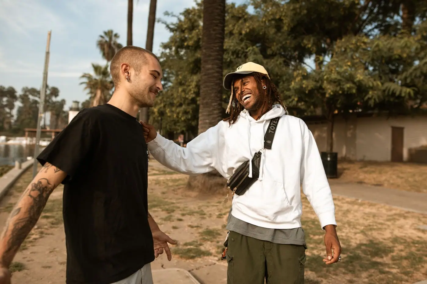 Two friends laughing together in a sunny Los Angeles park.