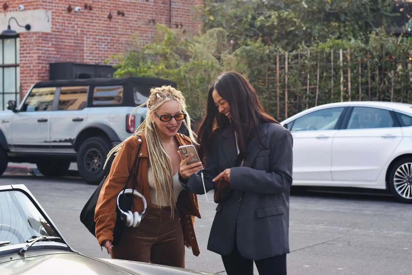 Two friends in Los Angeles smiling together over a smartphone.