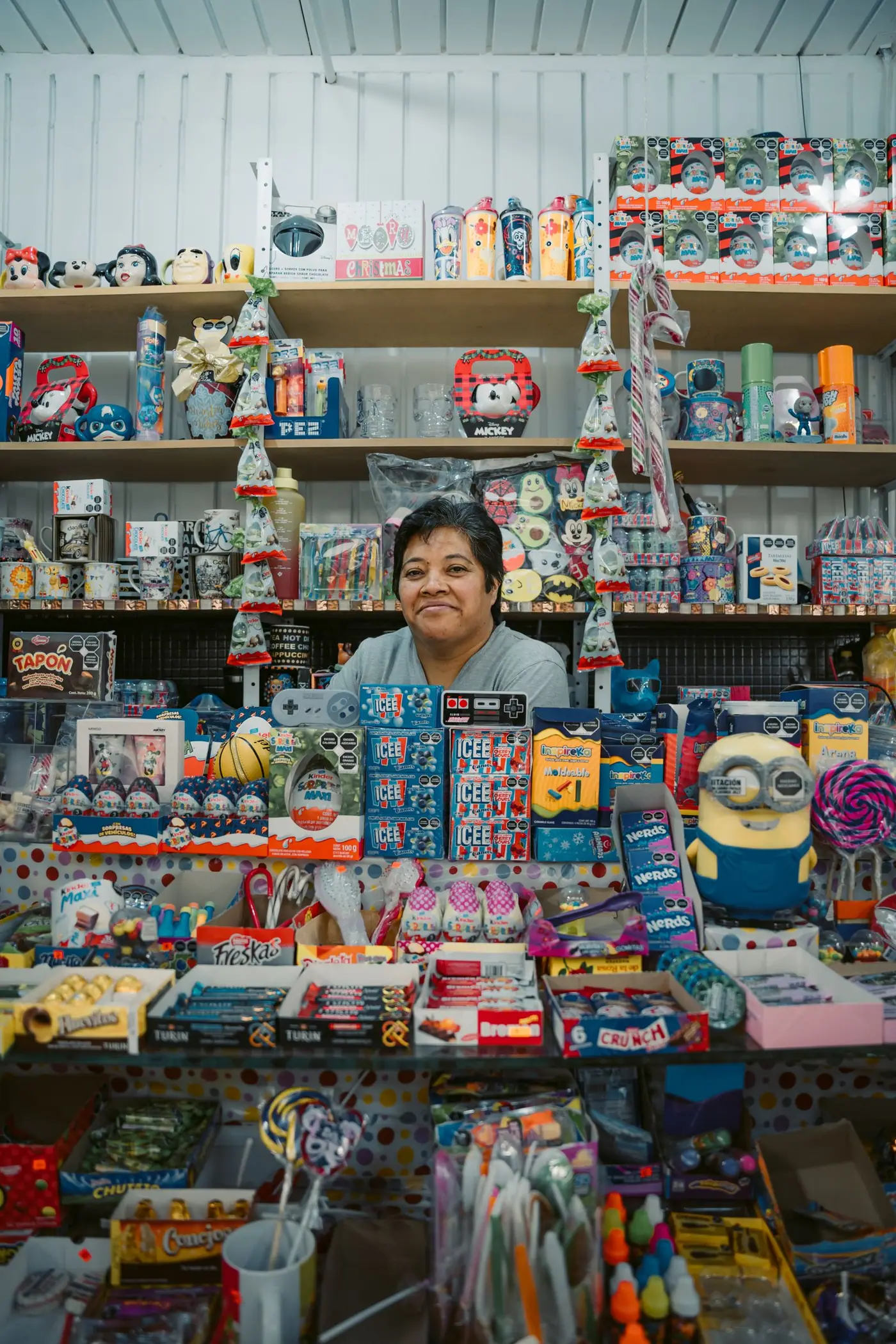 A woman standing among shelves of toys and goods in a colorful store in Mexico City.