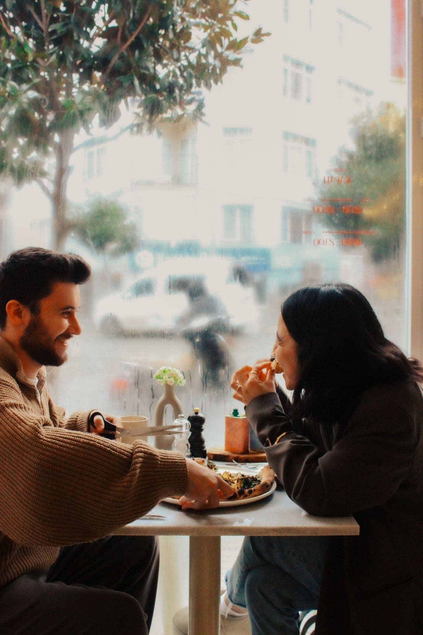 Two friends laughing together during a meal in a cafe.