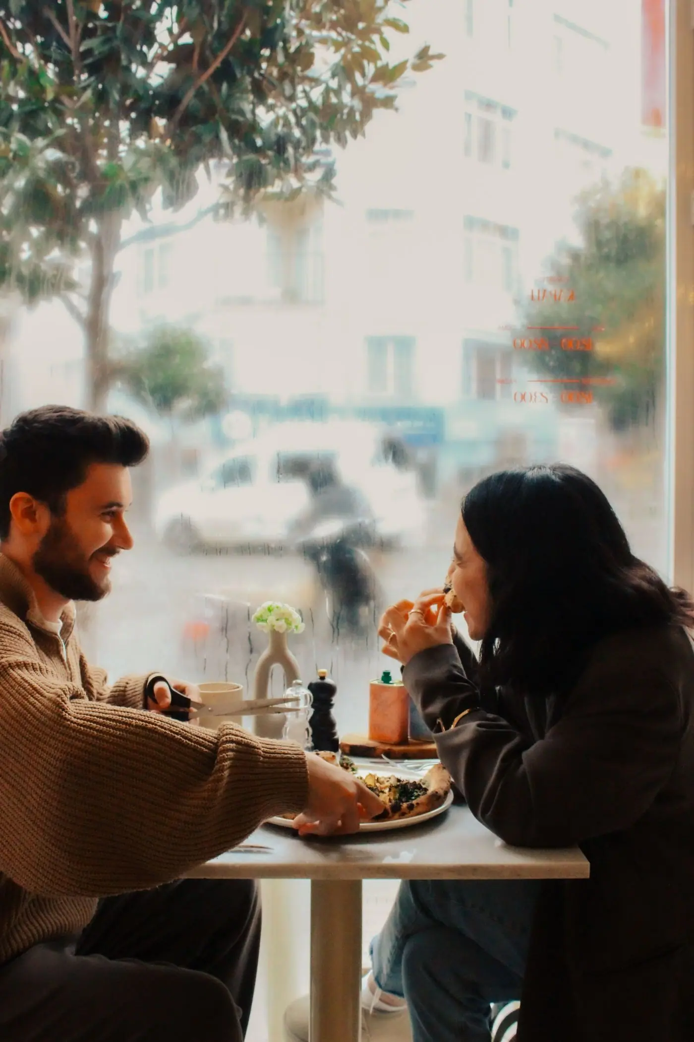 Two friends laughing together during a meal in a cafe.