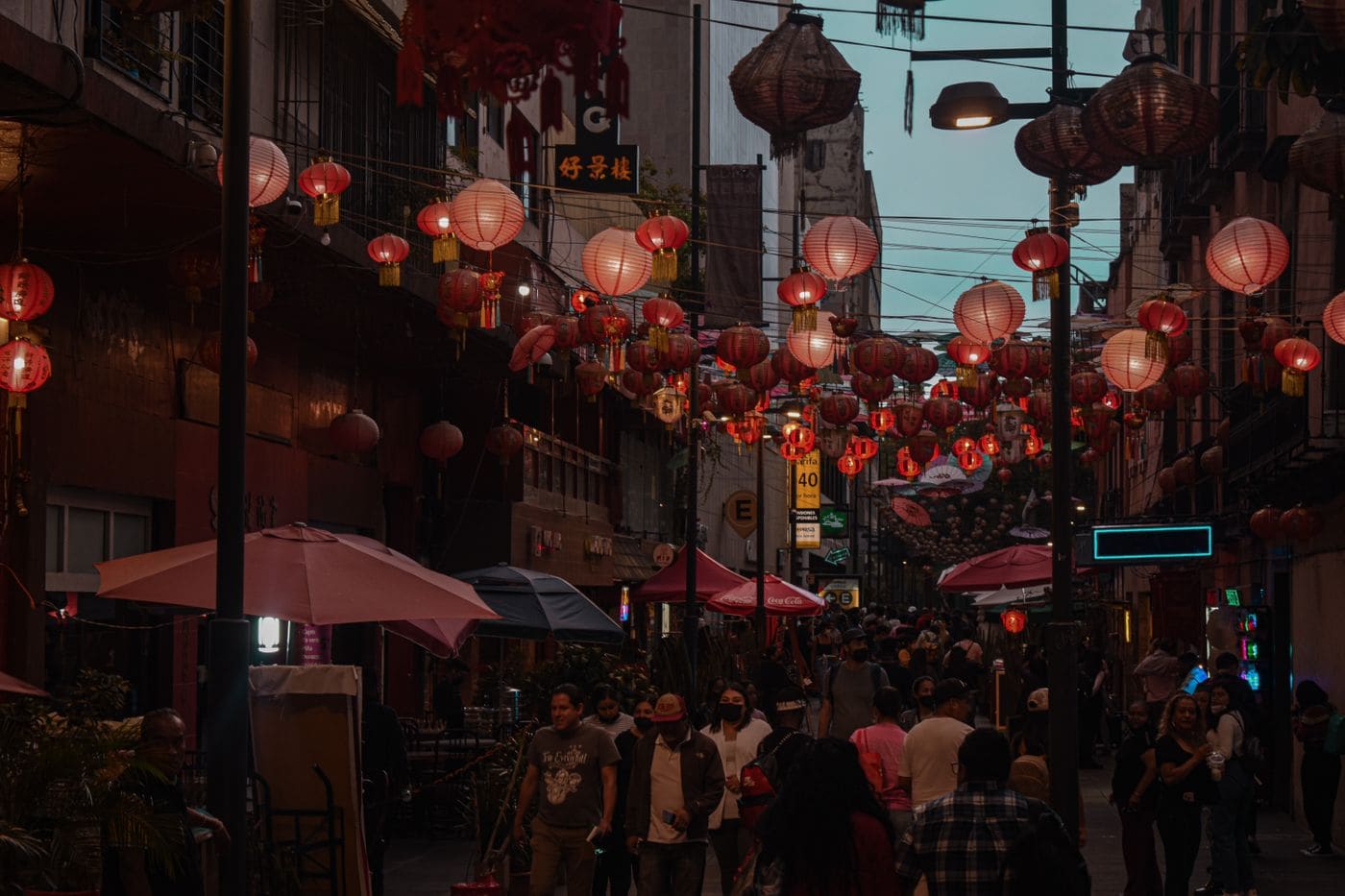 People walking under colorful lanterns on a busy Mexico City street at night.