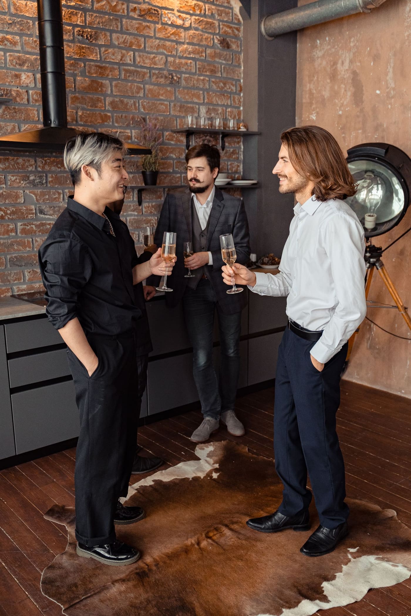 Three adults talking closely together at an indoor social gathering.
