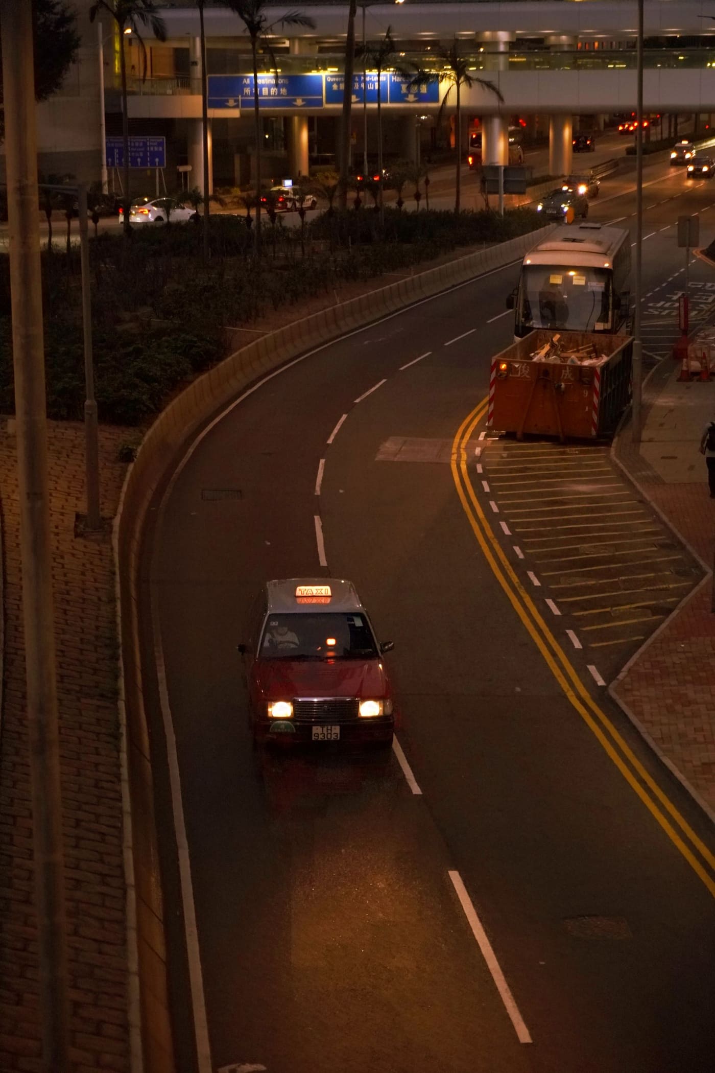 A taxi moving through a brightly lit city street at night.