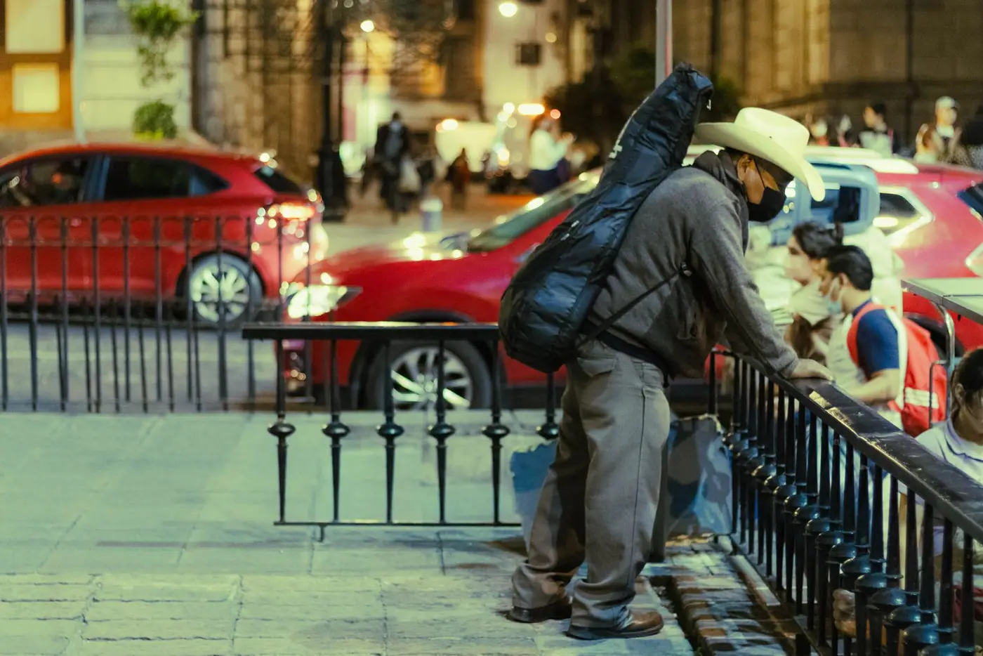 A street scene in Mexico City with a man carrying a guitar.