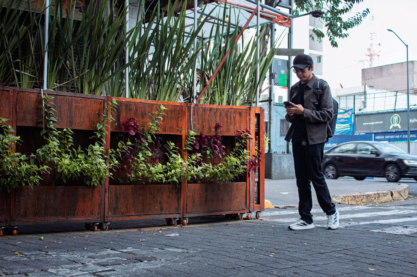 A young man checking a smartphone on a busy Mexico City street.