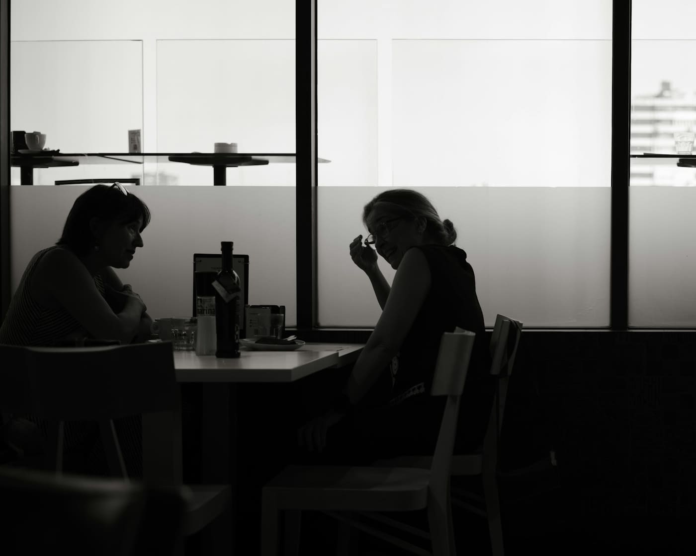 Two people sitting in silhouette at a table in a dimly lit room.