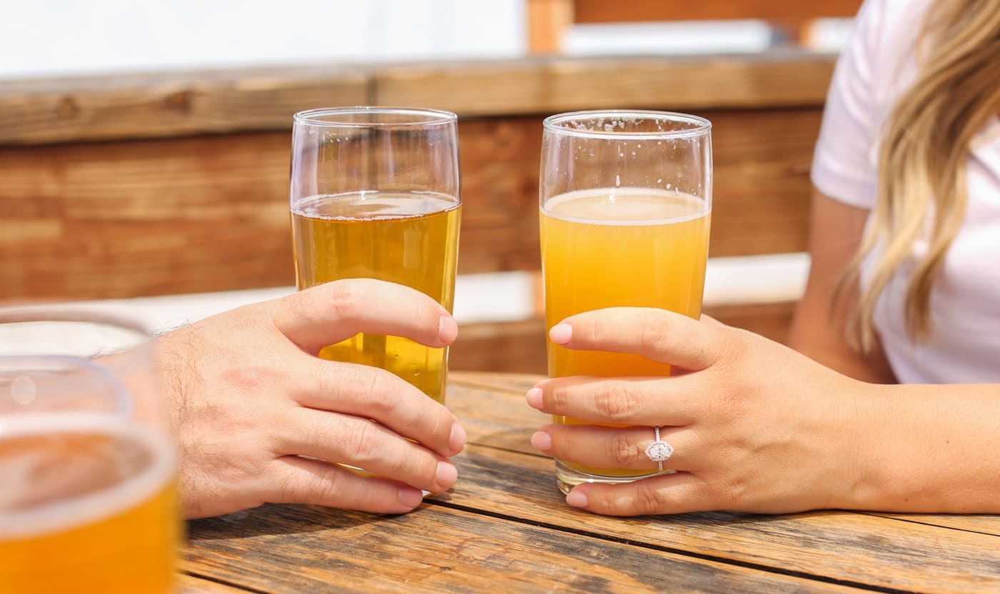 Hands raising glasses of beer in a toast.