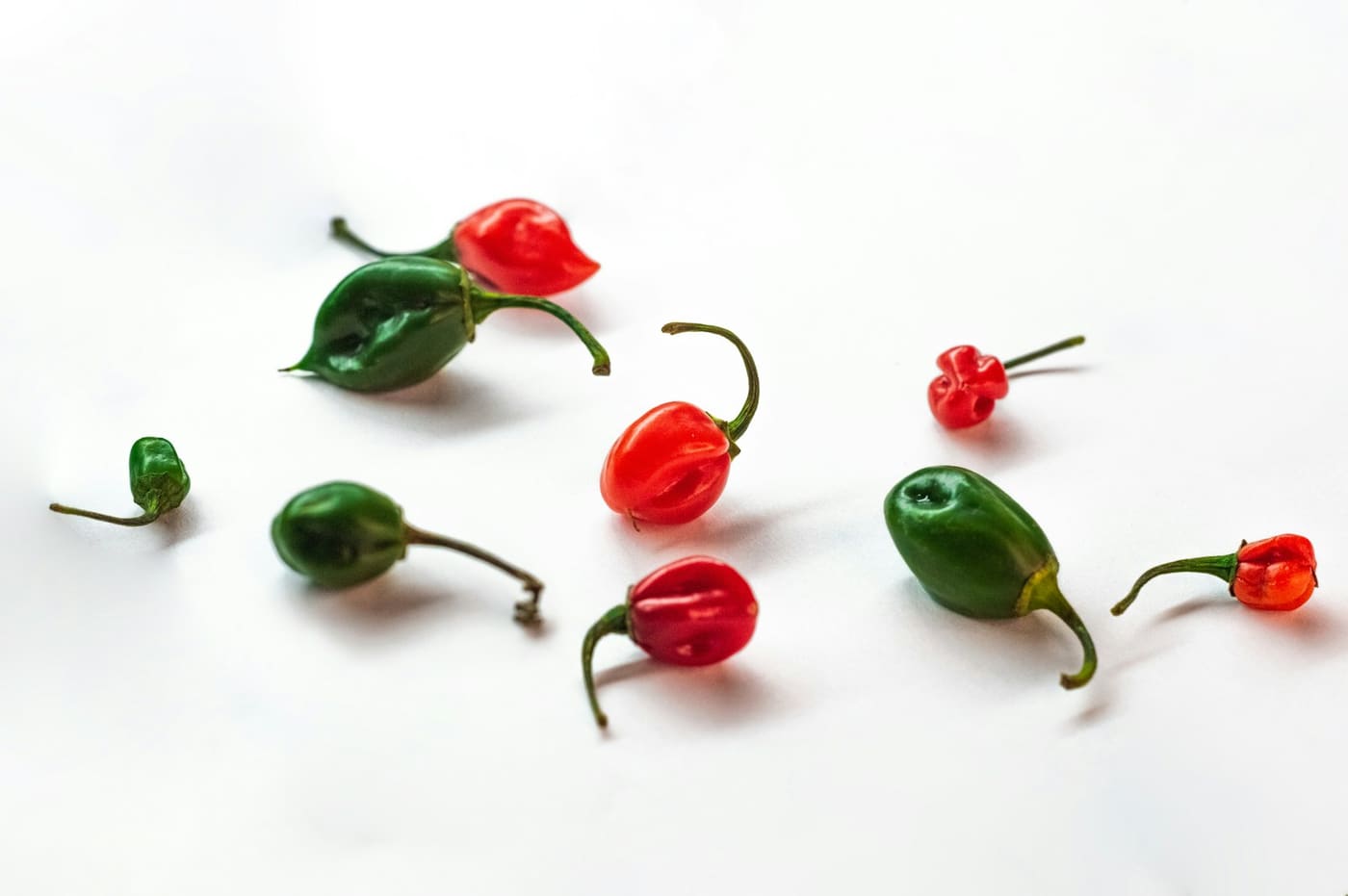Red and green peppers arranged on a white surface.