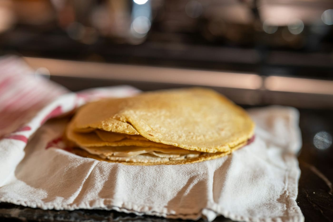 A stack of fresh corn tortillas resting on a folded cloth.