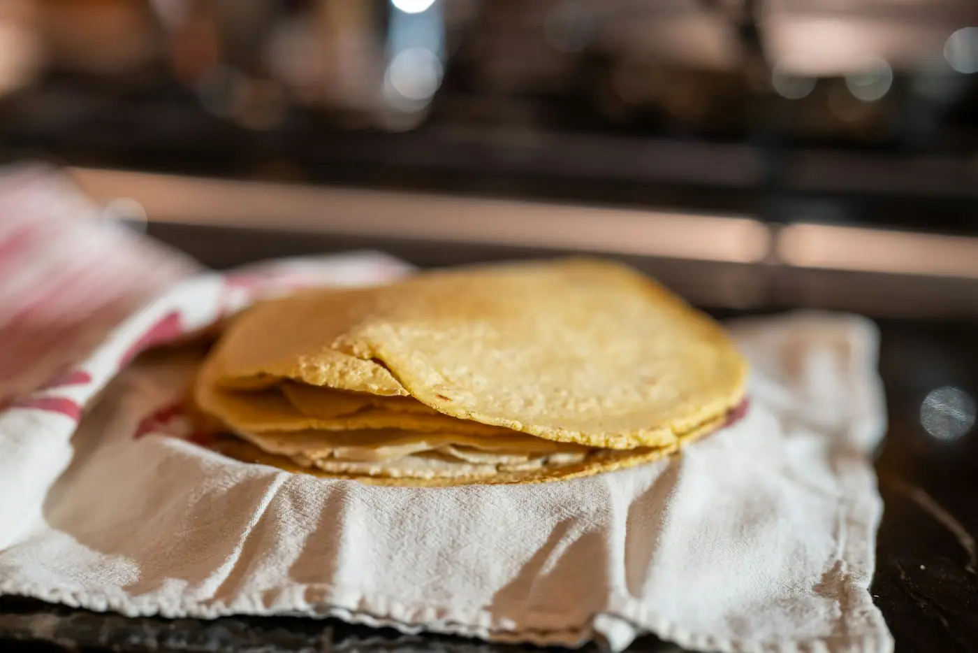 A stack of fresh corn tortillas resting on a folded cloth.
