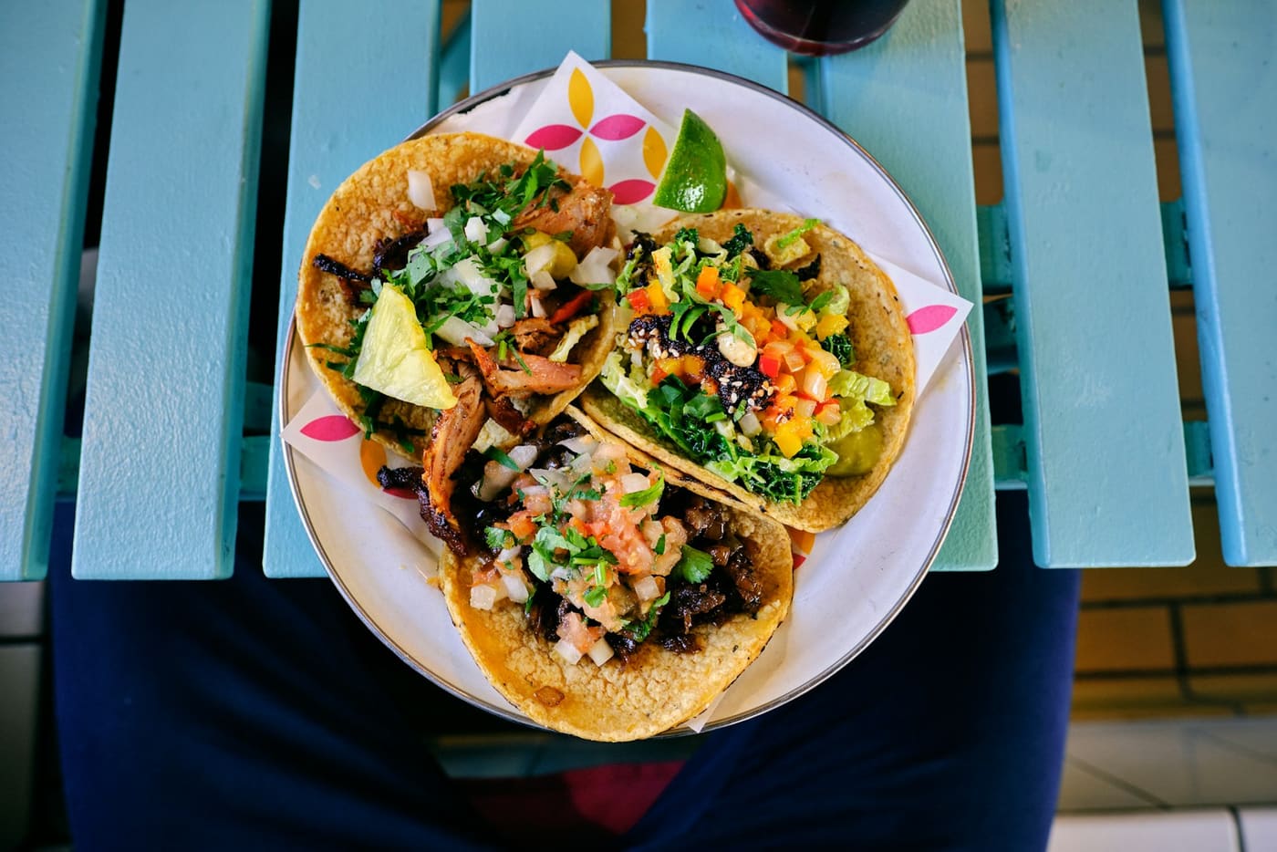 A plate of tacos with corn tortillas, chopped onion, and cilantro seen from above.