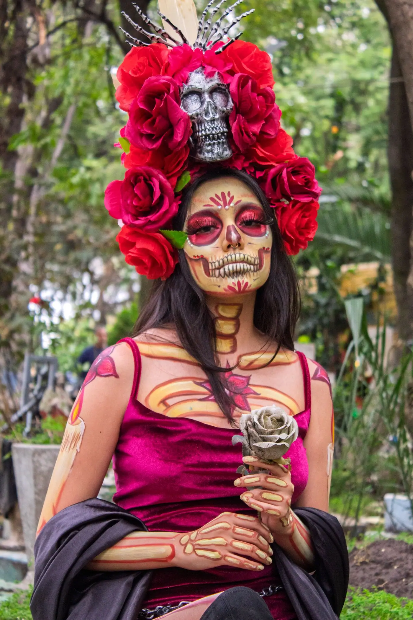 A woman in elegant La Catrina makeup and a wide feathered hat for Día de Muertos