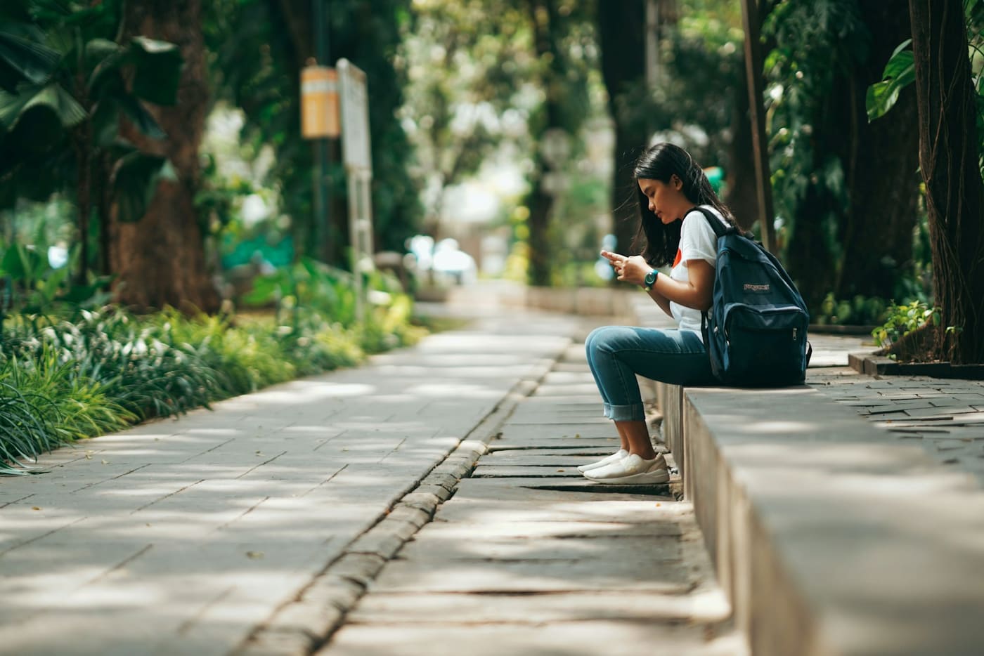 A person sitting and waiting at the edge of a street.
