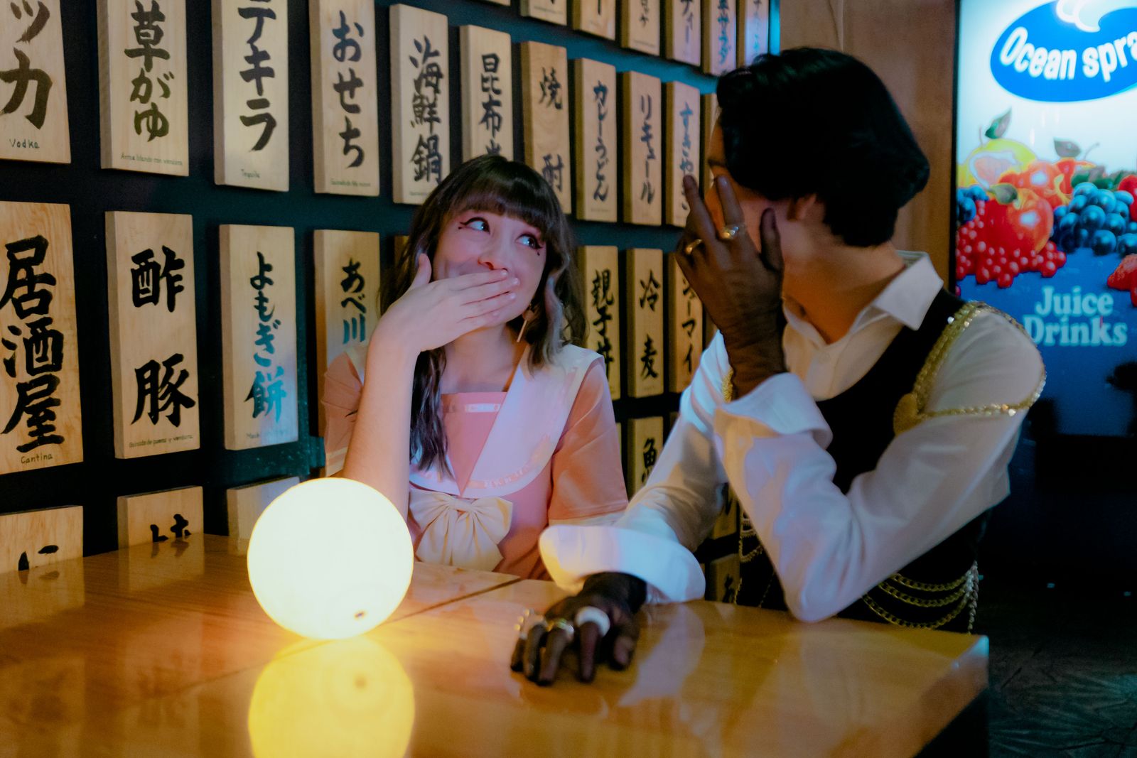 Two people sharing a secret at a restaurant table in Mexico City.