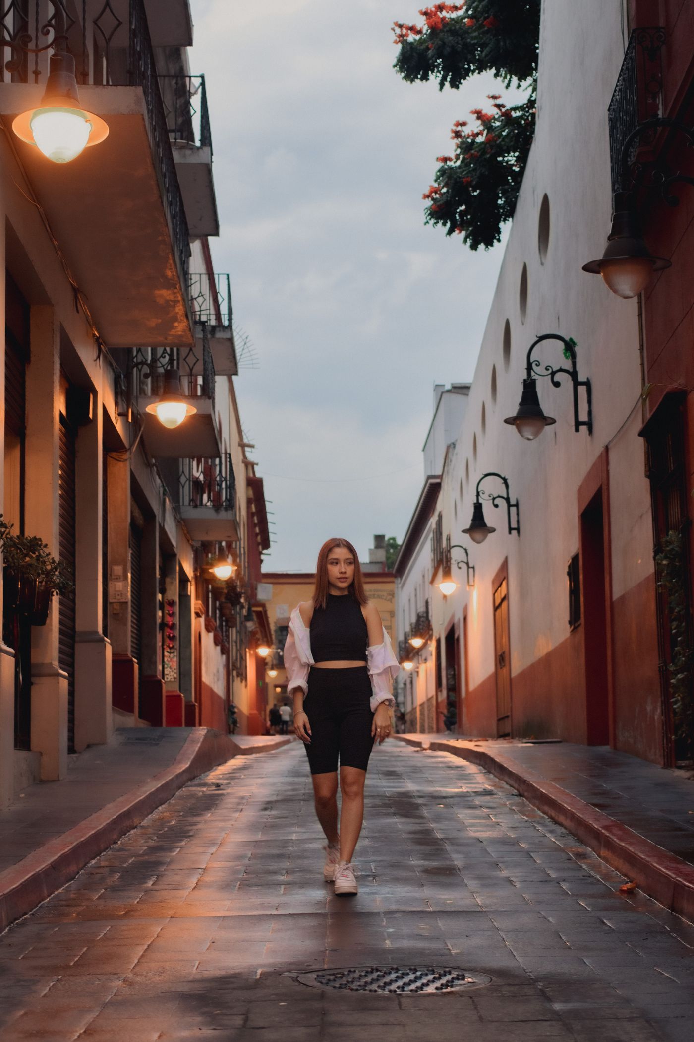A woman walking along a historic street in Mexico City at dusk.
