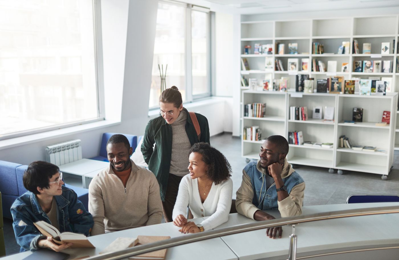 A group of friends having an animated conversation in a bright library.
