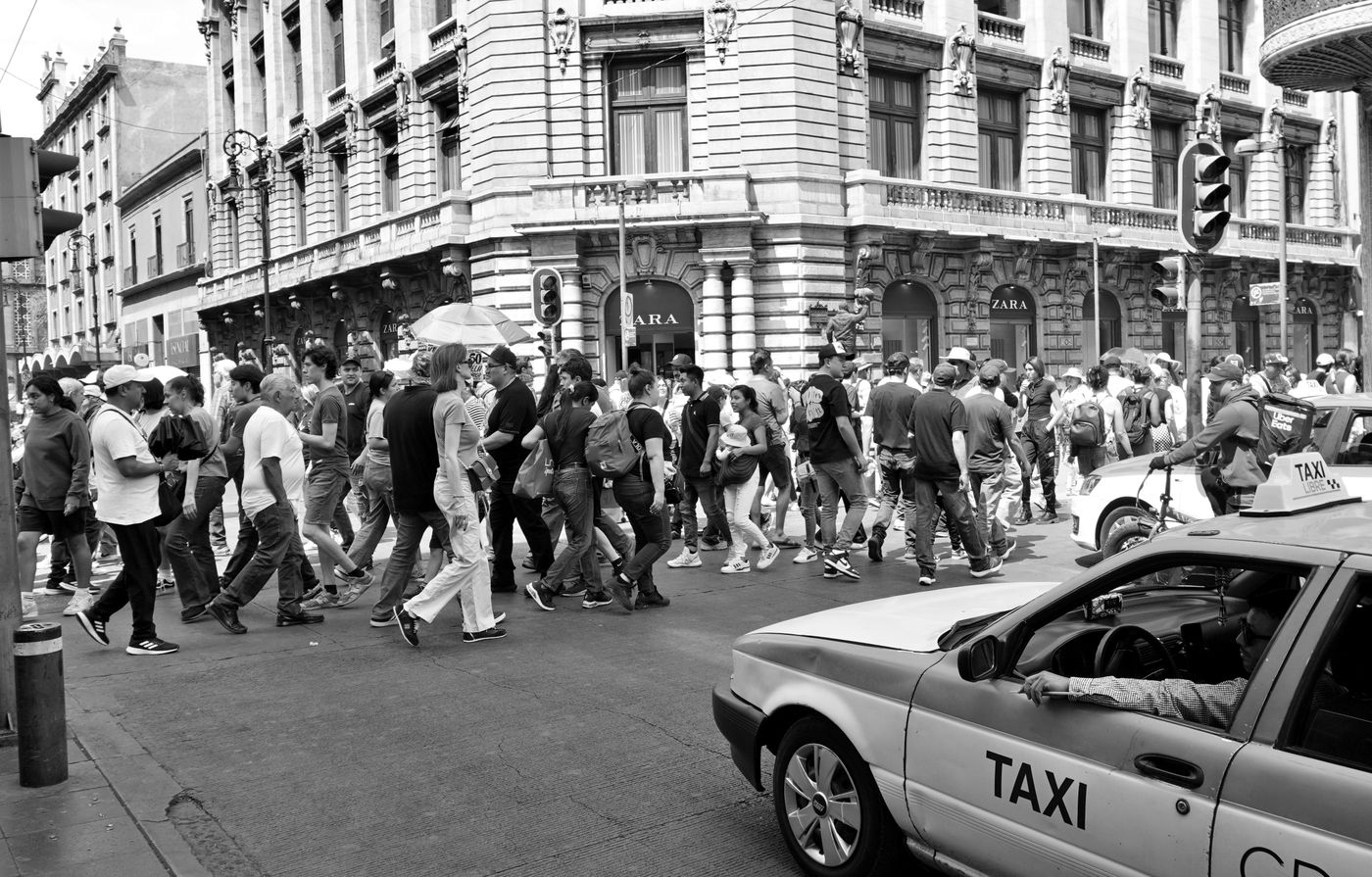 Pedestrians crossing a busy street in central Mexico City.