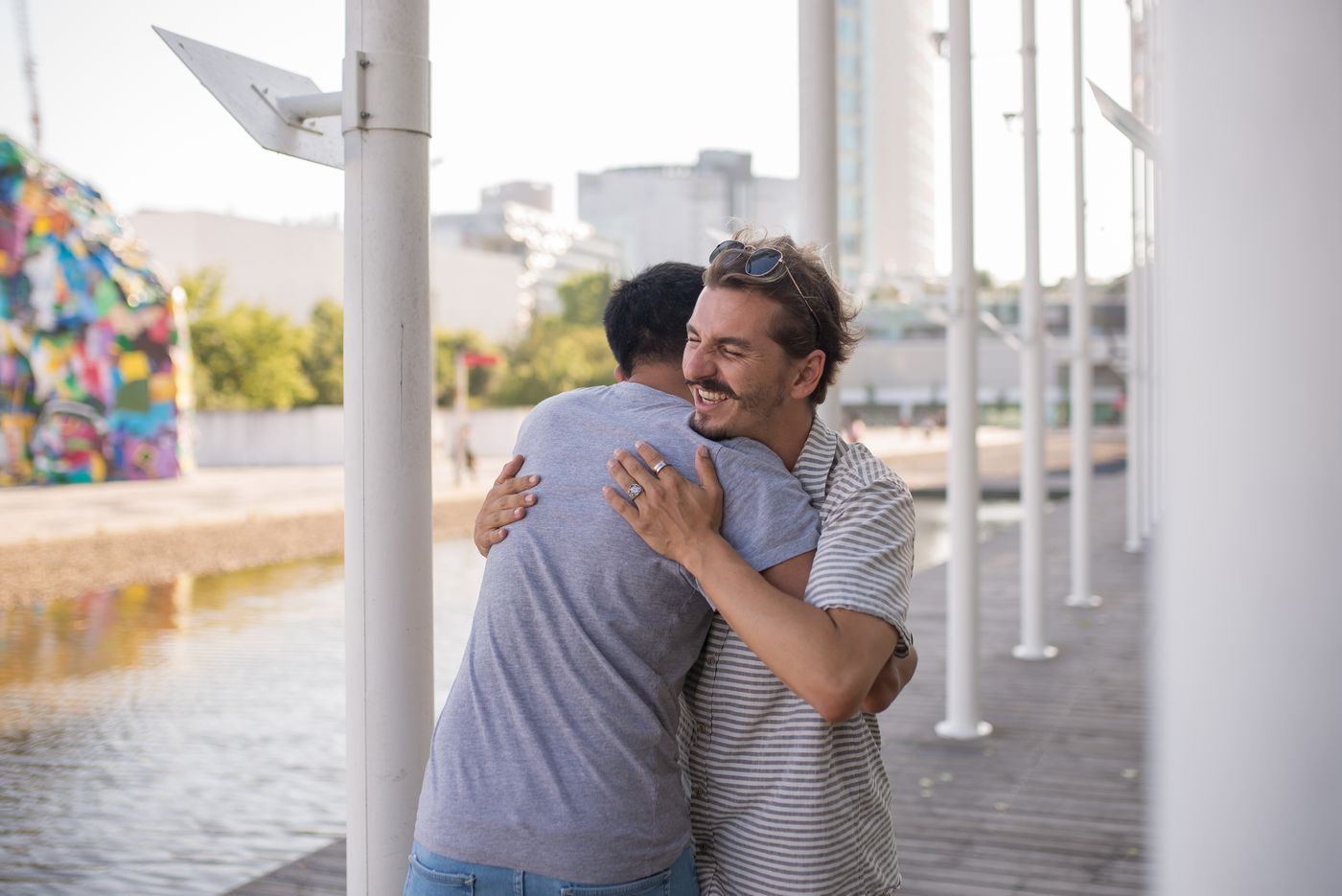 Two friends greeting each other with a warm hug on a city street.