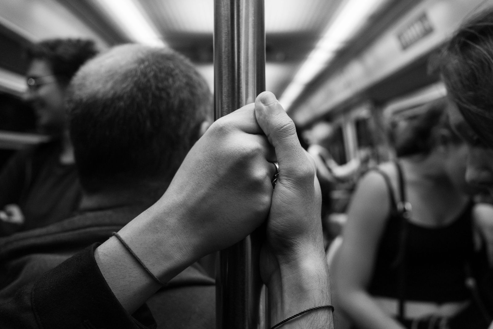 People holding a pole in a crowded metro train.