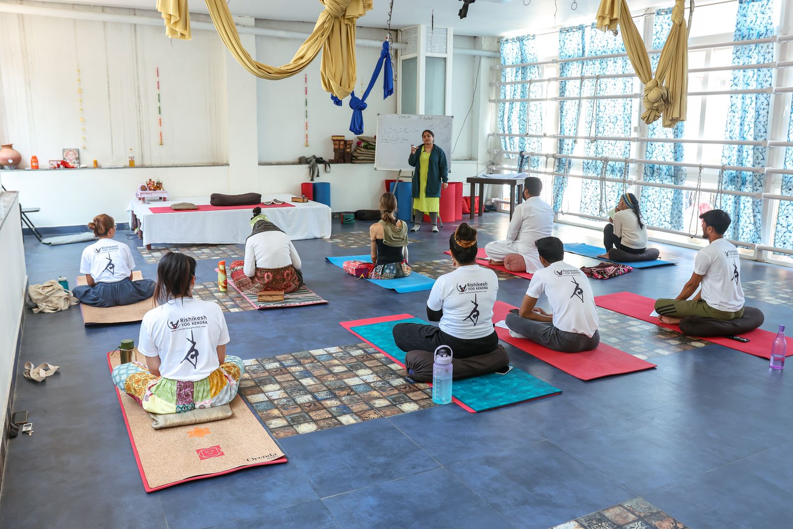 An instructor guiding adults through a yoga class in a bright studio.