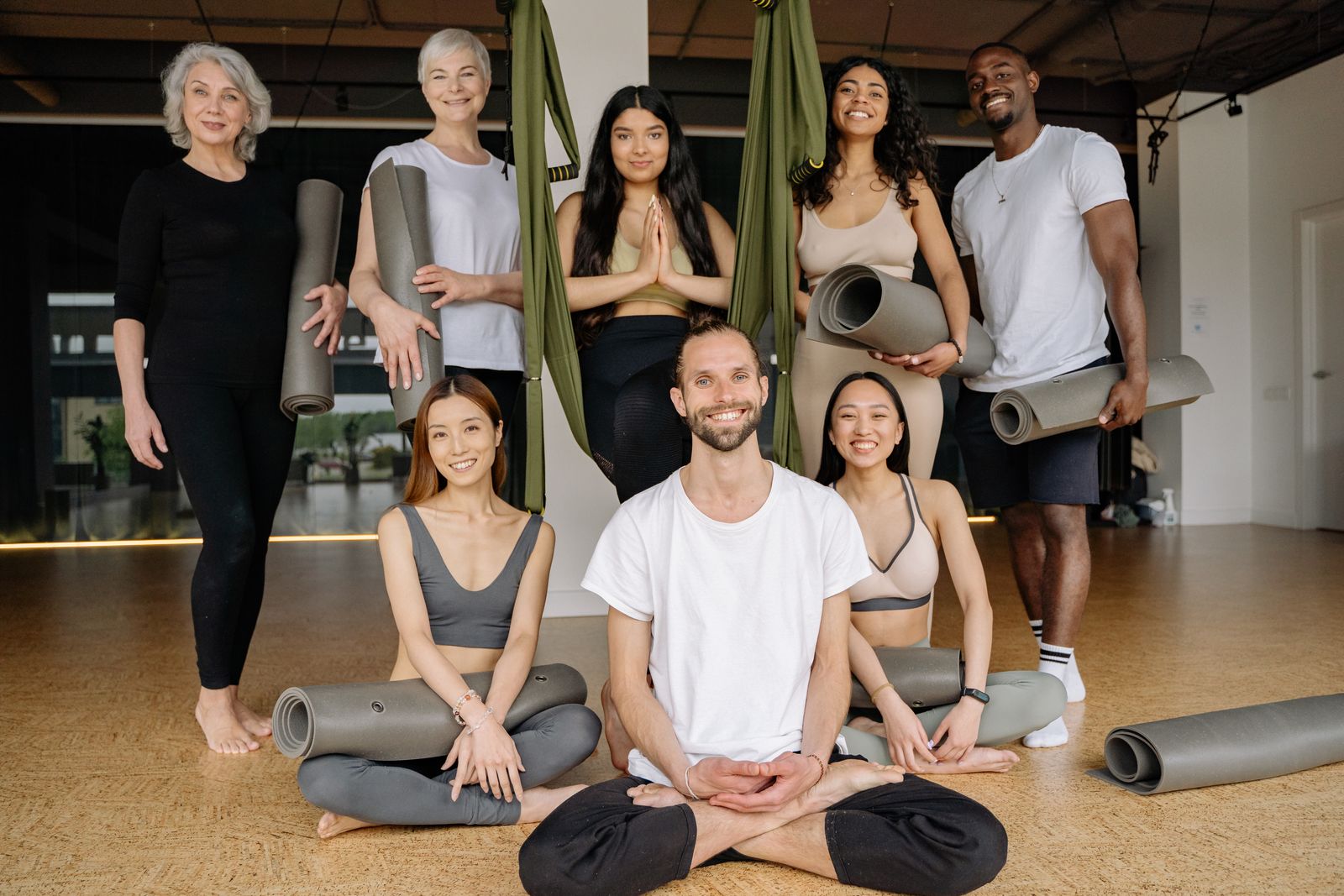A smiling group of adults taking a yoga class together.