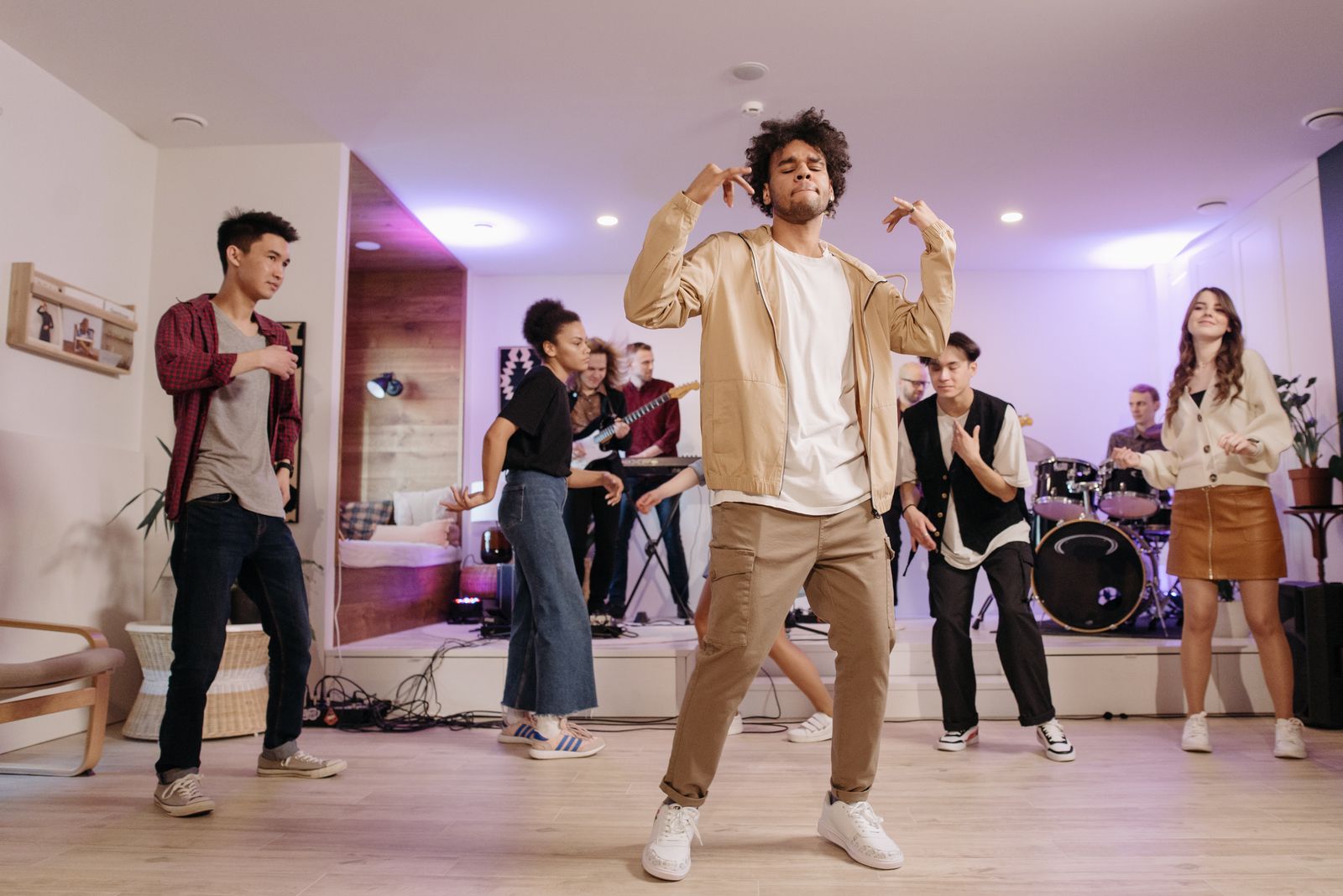 A group of adults dancing to live music at a home party.