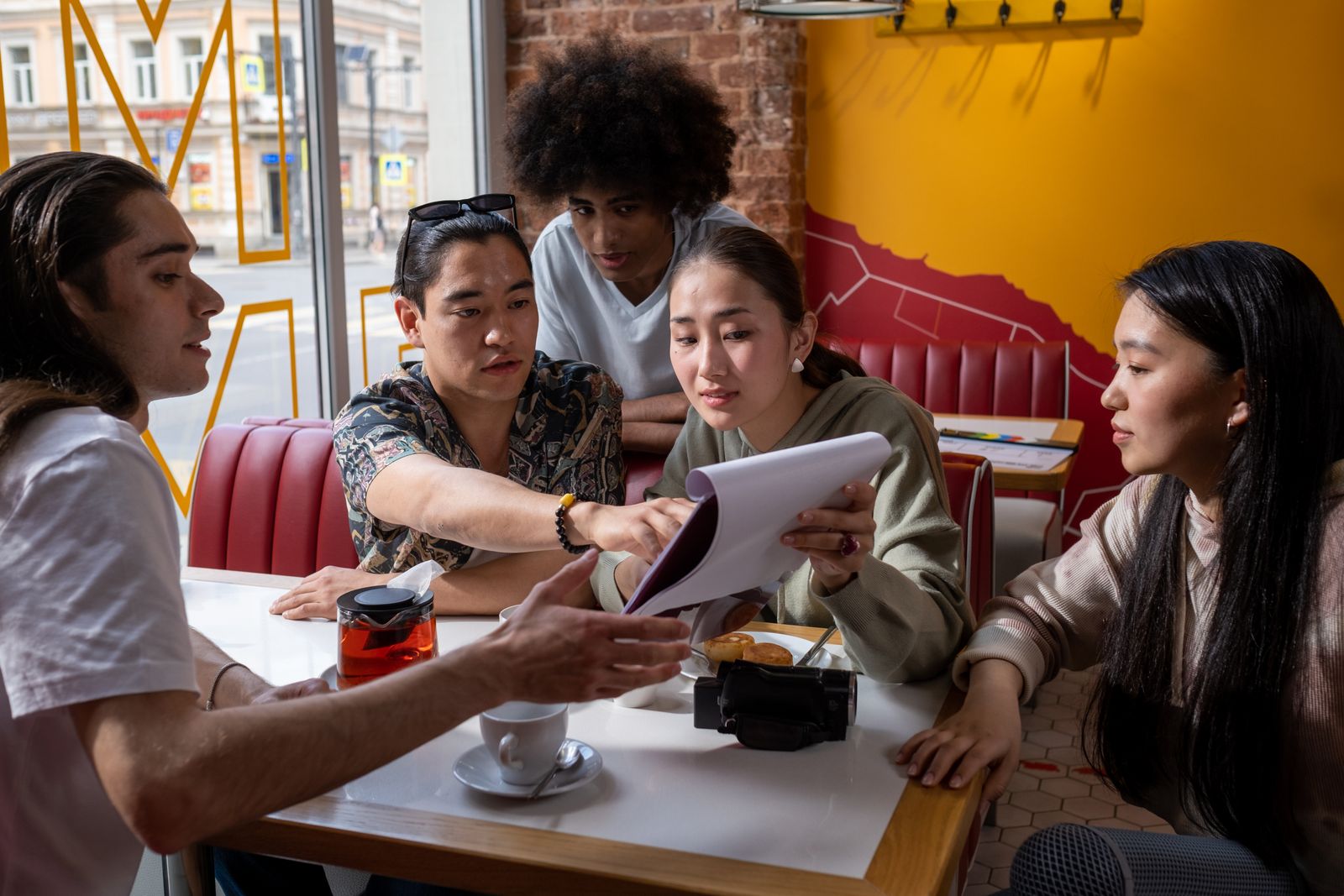 A small group of adults discussing a document around a cafe table.