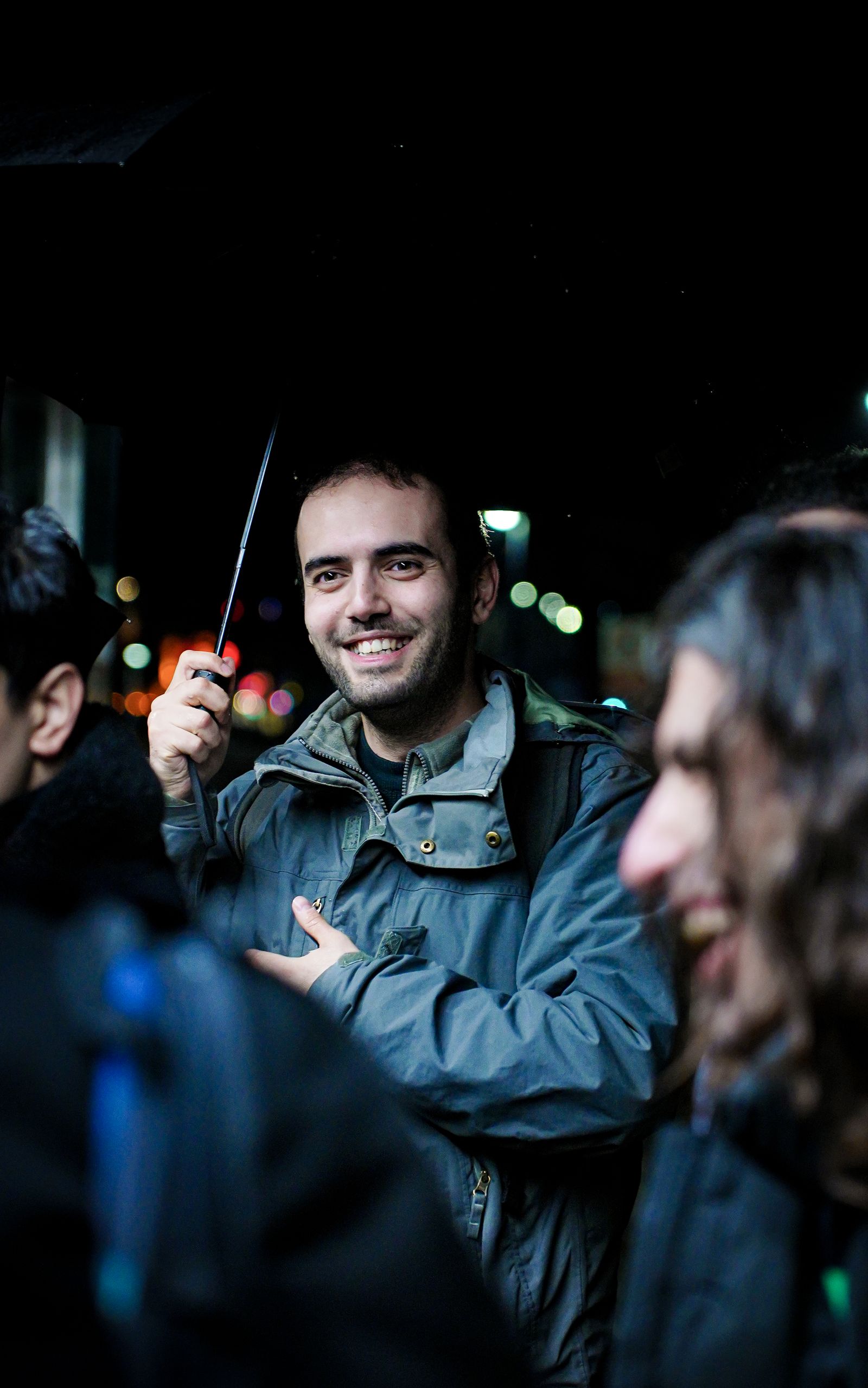 A group of friends laughing together on a city street at night.