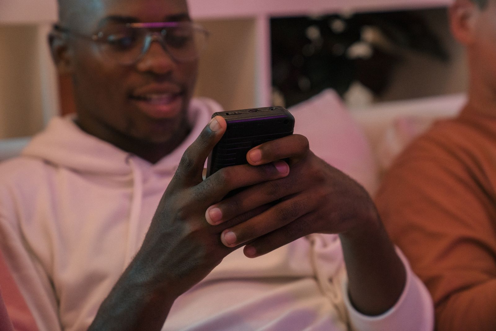 A person checking a smartphone while sitting with friends at a home gathering.