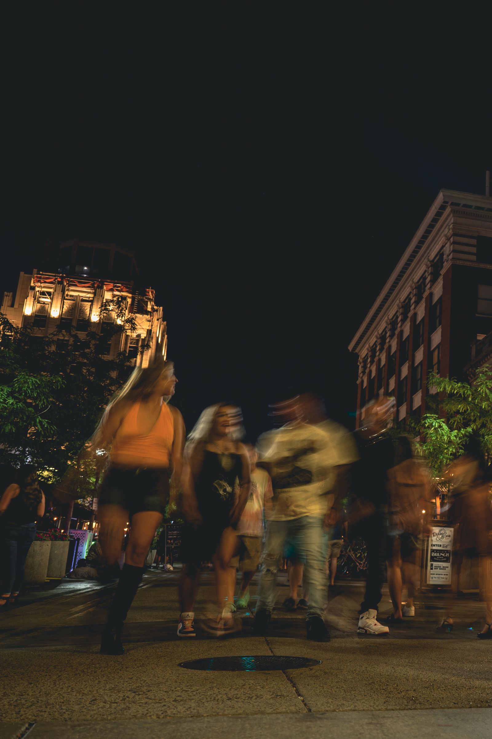 Friends walking together through a brightly lit city street at night.