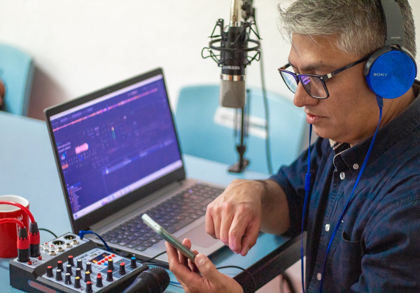 People recording a podcast around microphones at a table.