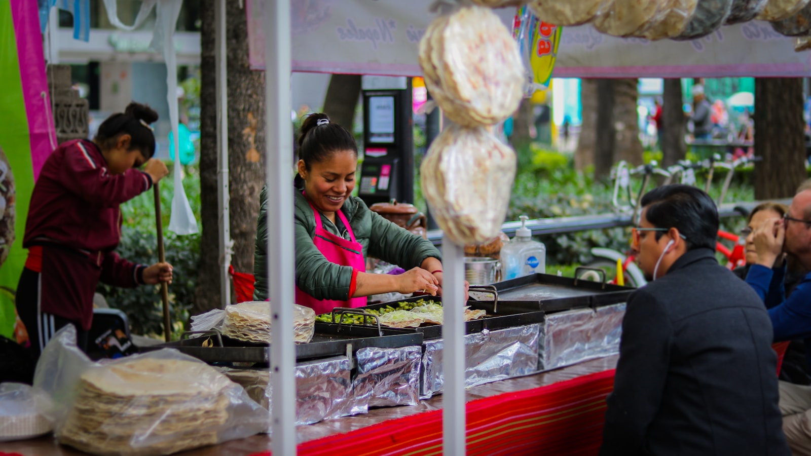 A woman serving food at a busy Mexican market stall.